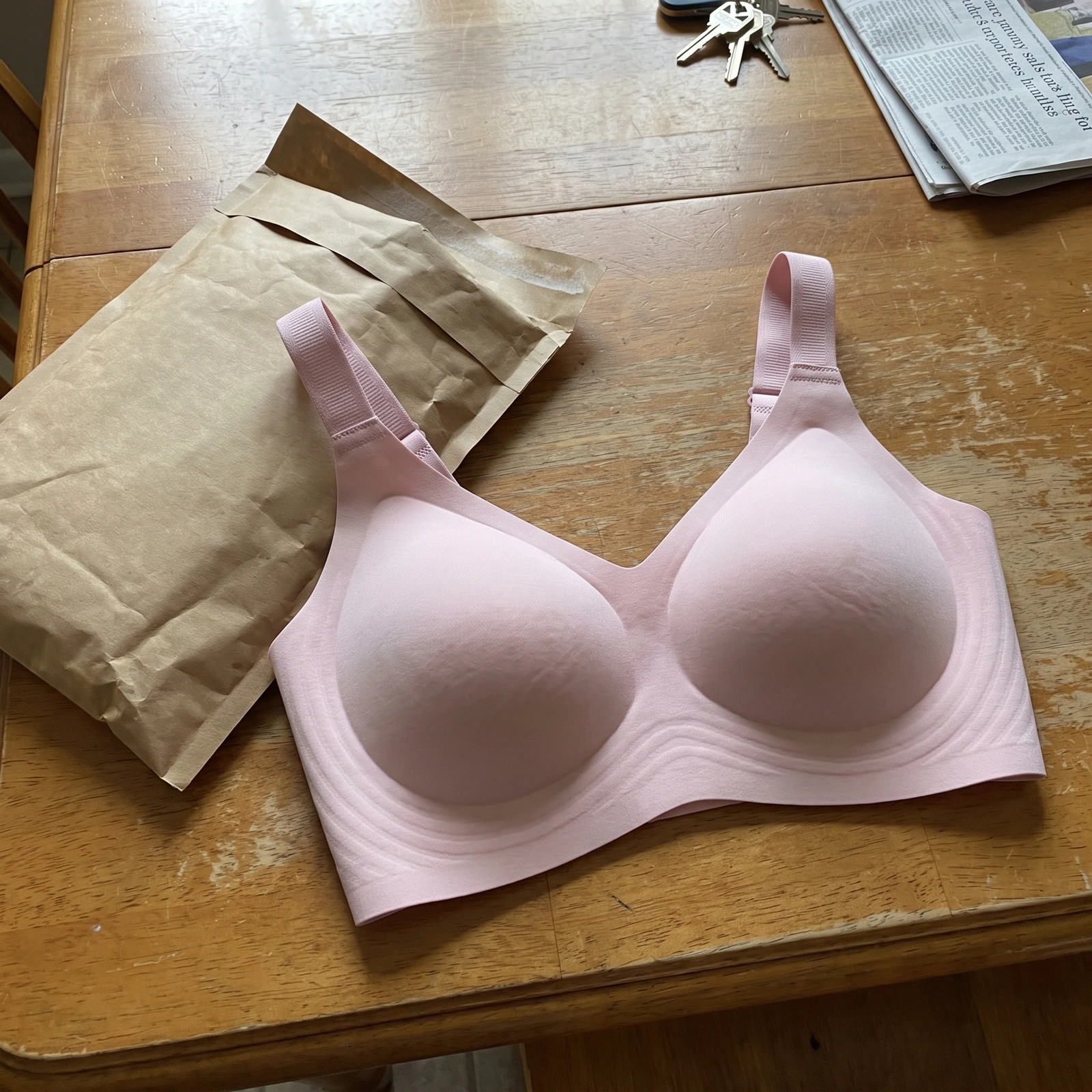 Le soutien-gorge rose sorti de son enveloppe d'expédition, sur une table en bois